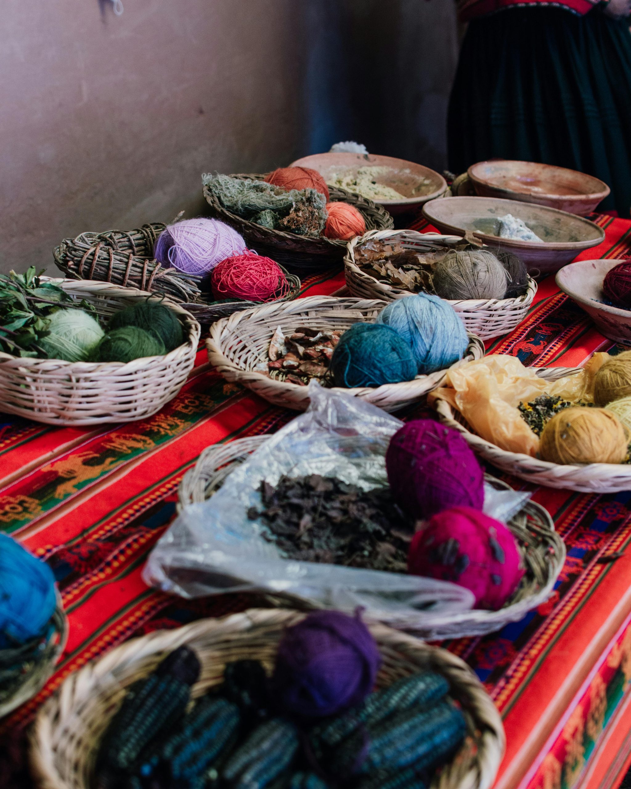 Vibrant display of traditional Peruvian textiles and natural dyes at a market in Cusco.